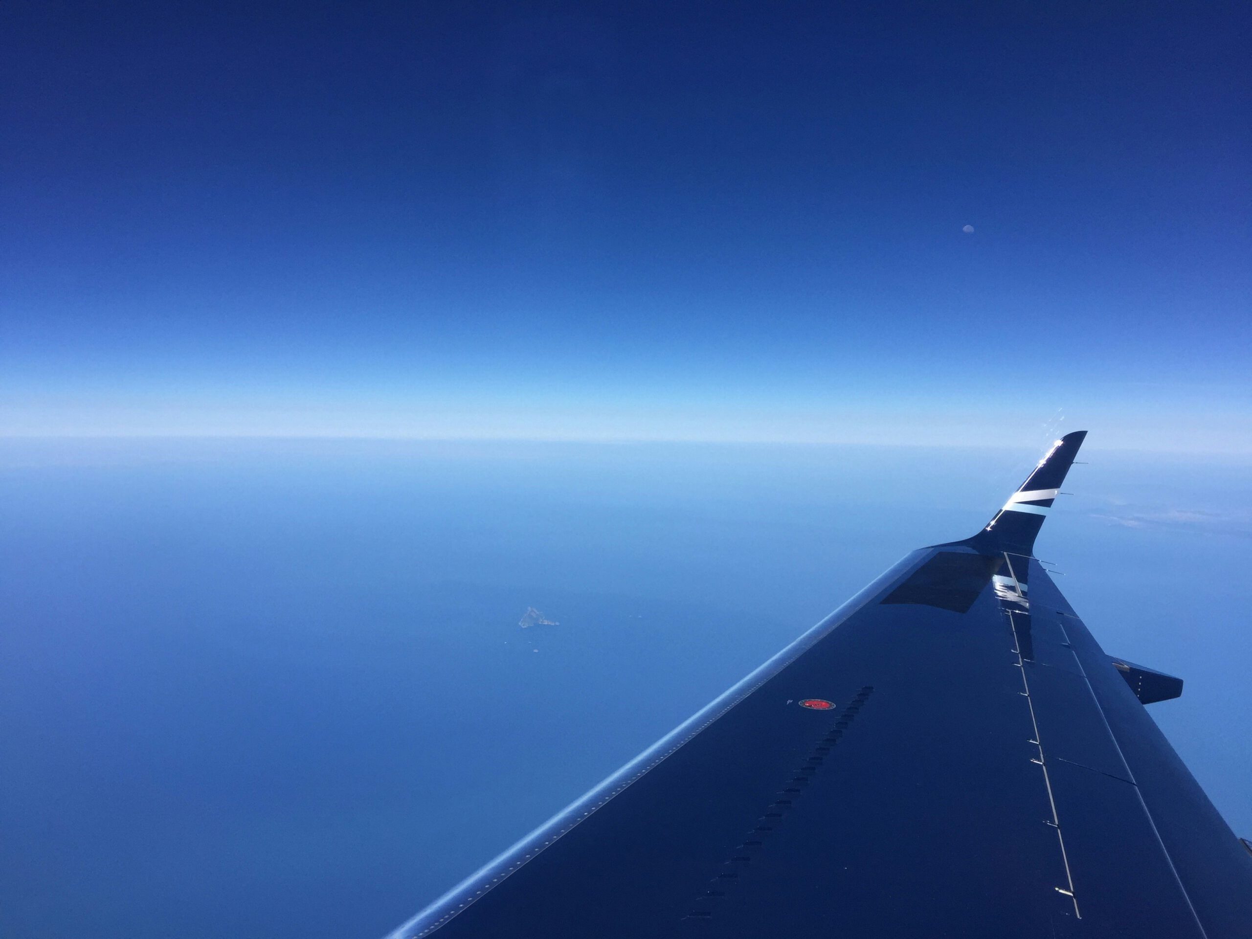 Flugzeugflügel über blauem Himmel und Meer